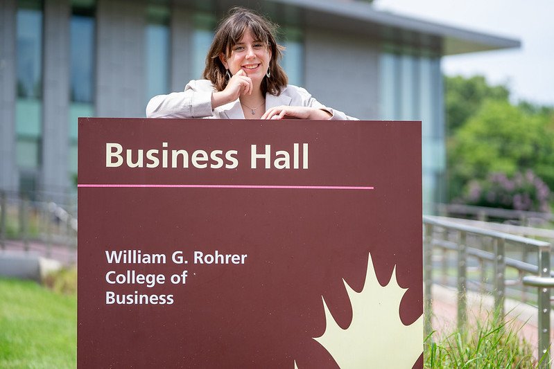 Student with Business Hall sign