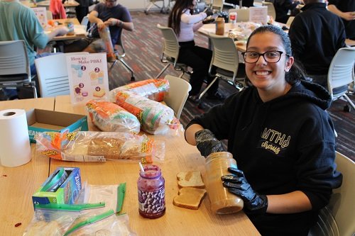 Student making peanut butter and jelly sandwiches 