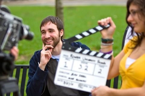 man on bench behind movie clap board